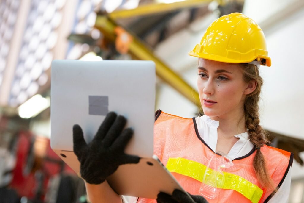 Female engineer using laptop checking on robotic arm machine